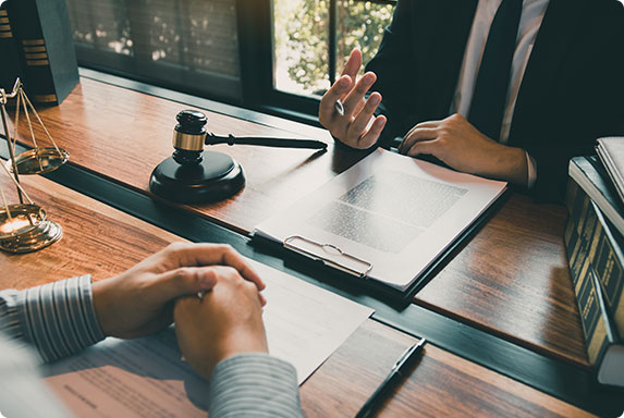 Lawyer discusses documents with a client, with a gavel and Scales of Justice, symbolizing legal consultation.