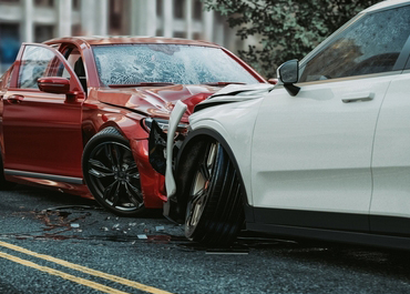 Red and white cars severely damaged in a head-on collision.