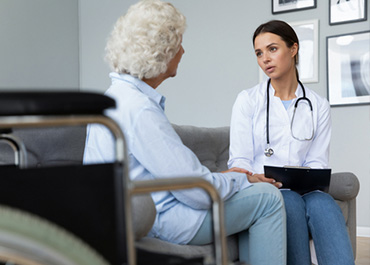 Doctor with a stethoscope consults an elderly woman in a wheelchair