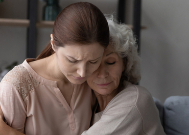 Grieving woman is gently comforted by a younger woman.
