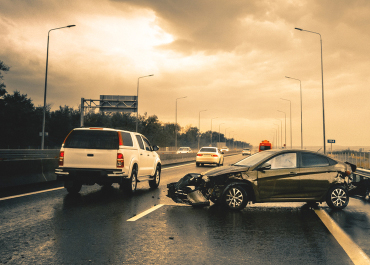 Two cars involved in a rear-end collision on a wet highway.