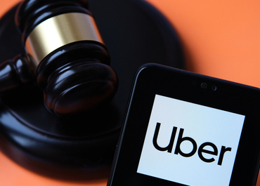 Gavel and scales of justice above a crumpled Uber car.