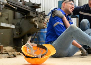 Construction worker clutching his injured shoulder on the factory floor.