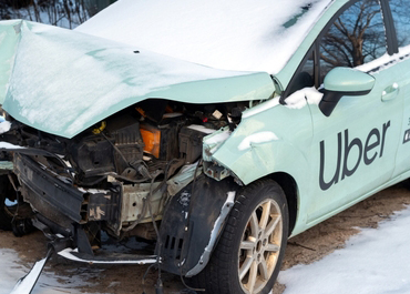 Severely damaged Uber car covered in snow after an accident.
