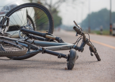 Crashed bicycle lying on the side of the road after a collision.