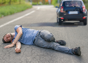 Man lying injured on the road after a hit-and-run accident, with the offending car driving away. Title: Dealing With Hit-And-Run Car Accidents.