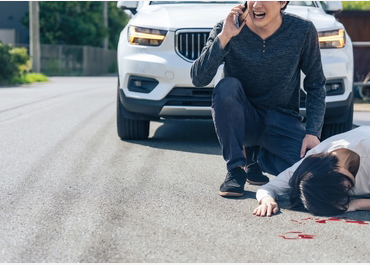 Man calling for help after hitting a pedestrian who is lying on the road with blood. Title: Punitive Compensation In Pedestrian Accident Cases.