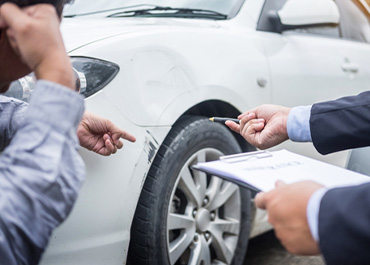Two people inspecting and documenting damage to a white car after an accident. Title: 8 Things Not To Say To Insurance Adjusters.