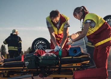 Paramedics attending to an injured person on a stretcher at an accident scene. Title: Most Common Catastrophic Injuries.