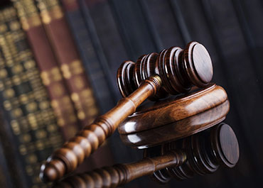 Gavel on a stack of law books with a scale of justice in the background. Title: Common Causes Of Pedestrian Fatalities.
