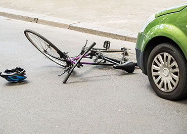 Bicycle lying on the road next to a green car after an accident. Title: Fight Back If Your Insurance Claim Is Denied?