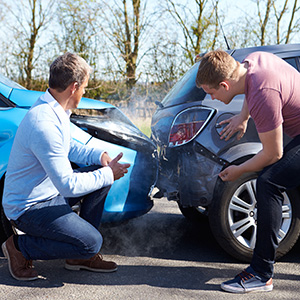 Two vehicles collide on road, man looking at cars – Edward Blinder, New Brunswick car accident lawyer